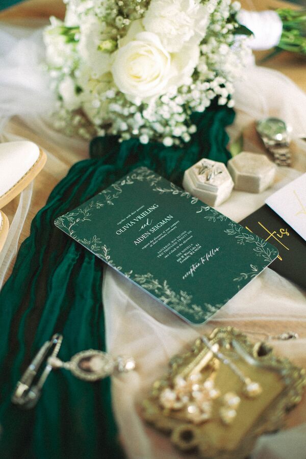 Wedding invitation with green velvet ribbon, white roses, and rings